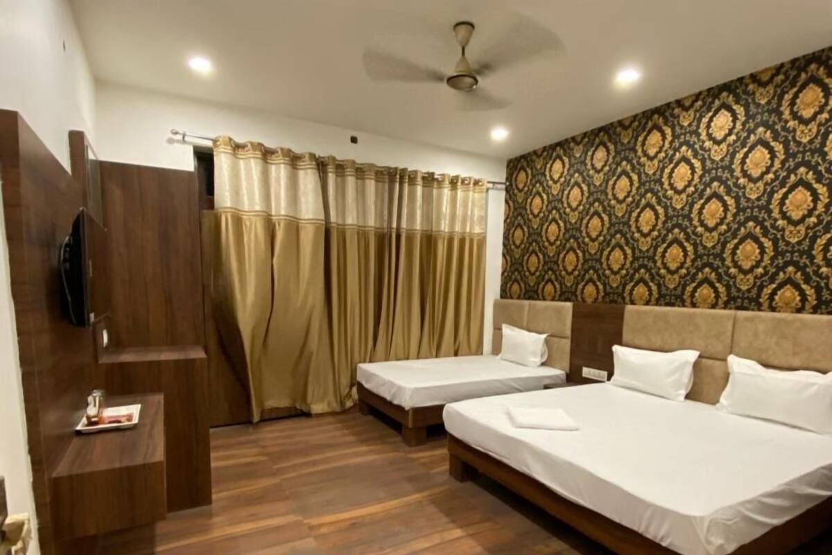 Habitación de hotel con dos camas, ventilador de techo, televisor y pared con diseño.