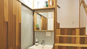 Ein Badezimmer mit Holzboden, Waschbecken mit Spiegel und Handtuch an der Wand.