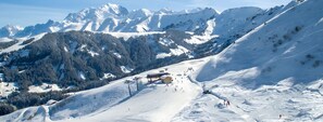 Eine verschneite Berglandschaft mit einem Skigebiet, einschließlich Skipisten, einer Berghütte und einem Sessellift.