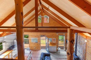 Ein Holzinterieur mit hohen Decken, einer Couch, einem Tisch und einer Küchenzeile.