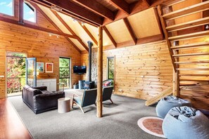 Ein Blockhaus-Interieur mit Kamin, Sofa, Sesseln und einem Fernseher.