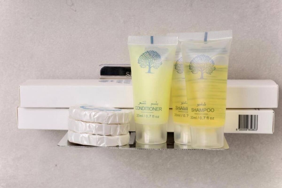 A shelf with two tubes of conditioner and shampoo, and a pack of white bars.