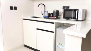 A compact kitchenette with a microwave, coffee maker, and water bottles on the counter. - Moodar (Madinah)