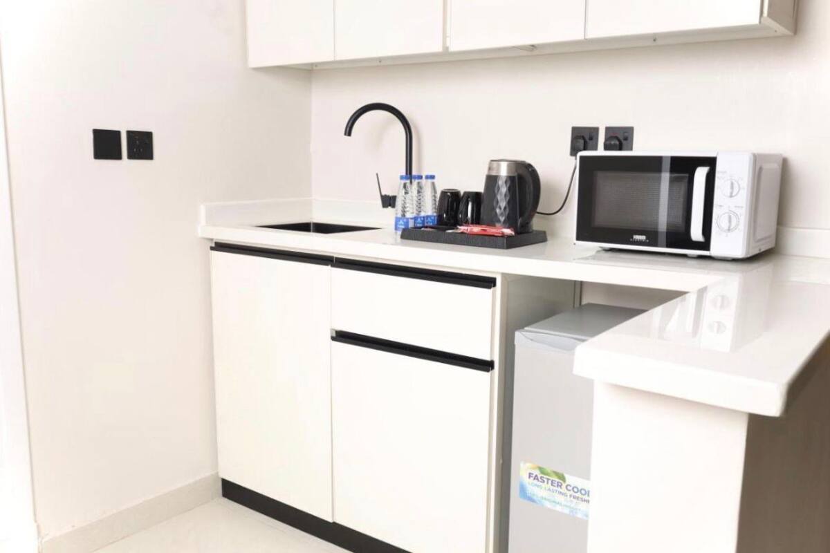 A compact kitchenette with a microwave, coffee maker, and water bottles on the counter.
