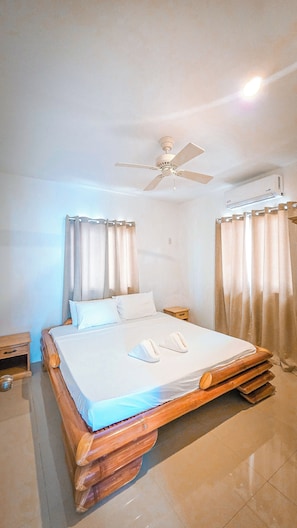 A bedroom with a bed, a ceiling fan, curtains, and a wall-mounted air conditioning unit.