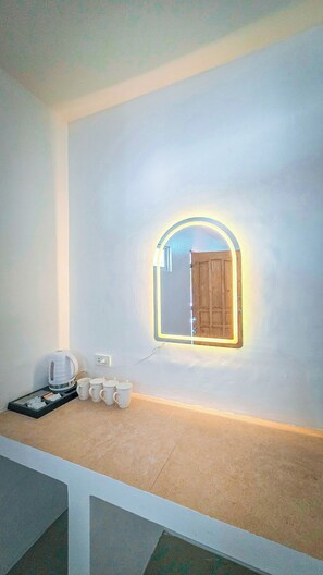 A room with a white wall, a wooden door, a coffee maker, and a tray with cups and a kettle. - Beyond Island Resort (Moalboal)
