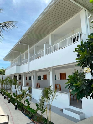 A two-story building with a white exterior, multiple balconies, and a covered outdoor area with plants. - Beyond Island Resort (Moalboal)