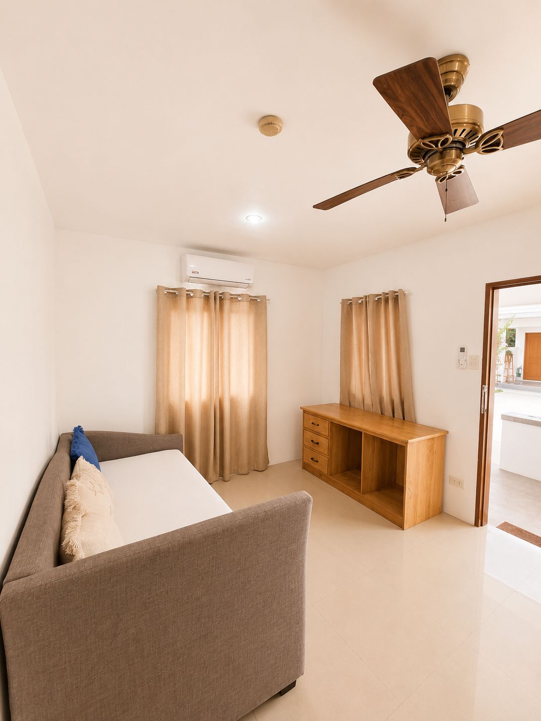 A hotel room with a bed, a desk, a ceiling fan, and curtains.