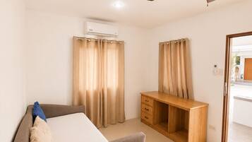 A hotel room with a bed, a desk, a ceiling fan, and curtains.