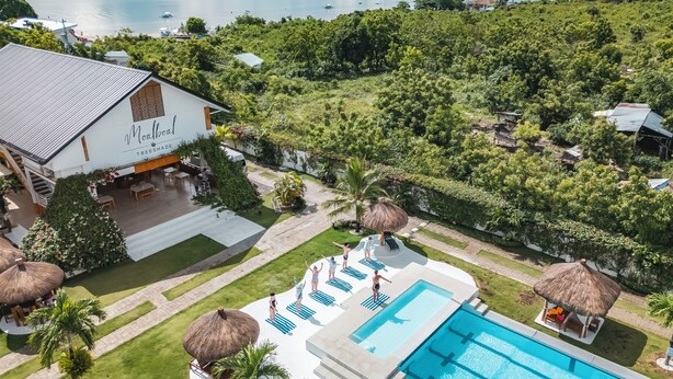 A resort with a swimming pool, lounge chairs, and a view of the sea.