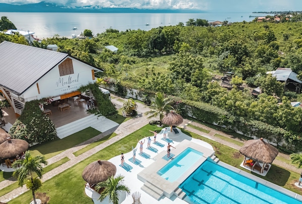 A resort with a swimming pool, lounge chairs, and a view of the sea.