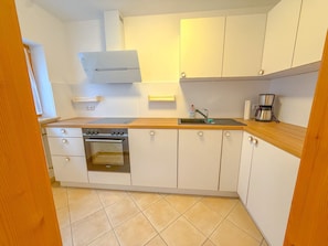 Een keuken met witte kasten, een oven van roestvrij staal, een houten aanrecht en een koffiezetapparaat.