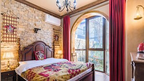 A bedroom with a large bed, a stone wall, a window with curtains, and a chandelier. - Beijing Magic Villa (Tongzhou)