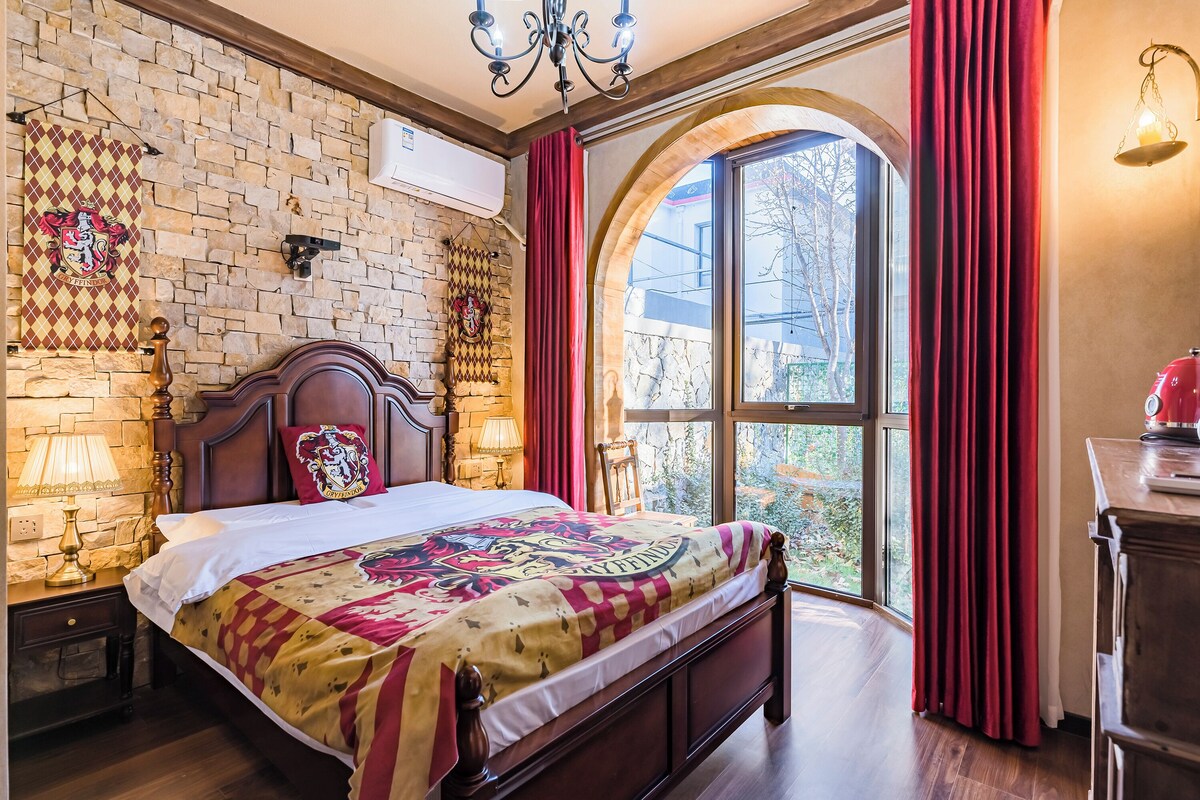 Ein Schlafzimmer mit einem großen Bett, einer Steinwand, einem Fenster mit Vorhängen und einer Kristallleuchter.