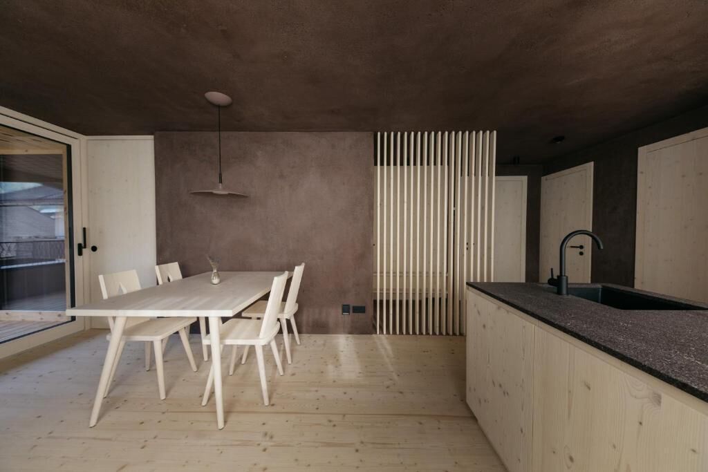 Una cucina moderna con un tavolo e sedie in legno, un piano di lavoro nero e una finestra con vista.