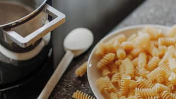 Un plan de travail de cuisine avec une casserole, un bol de pâtes et une cuillère.