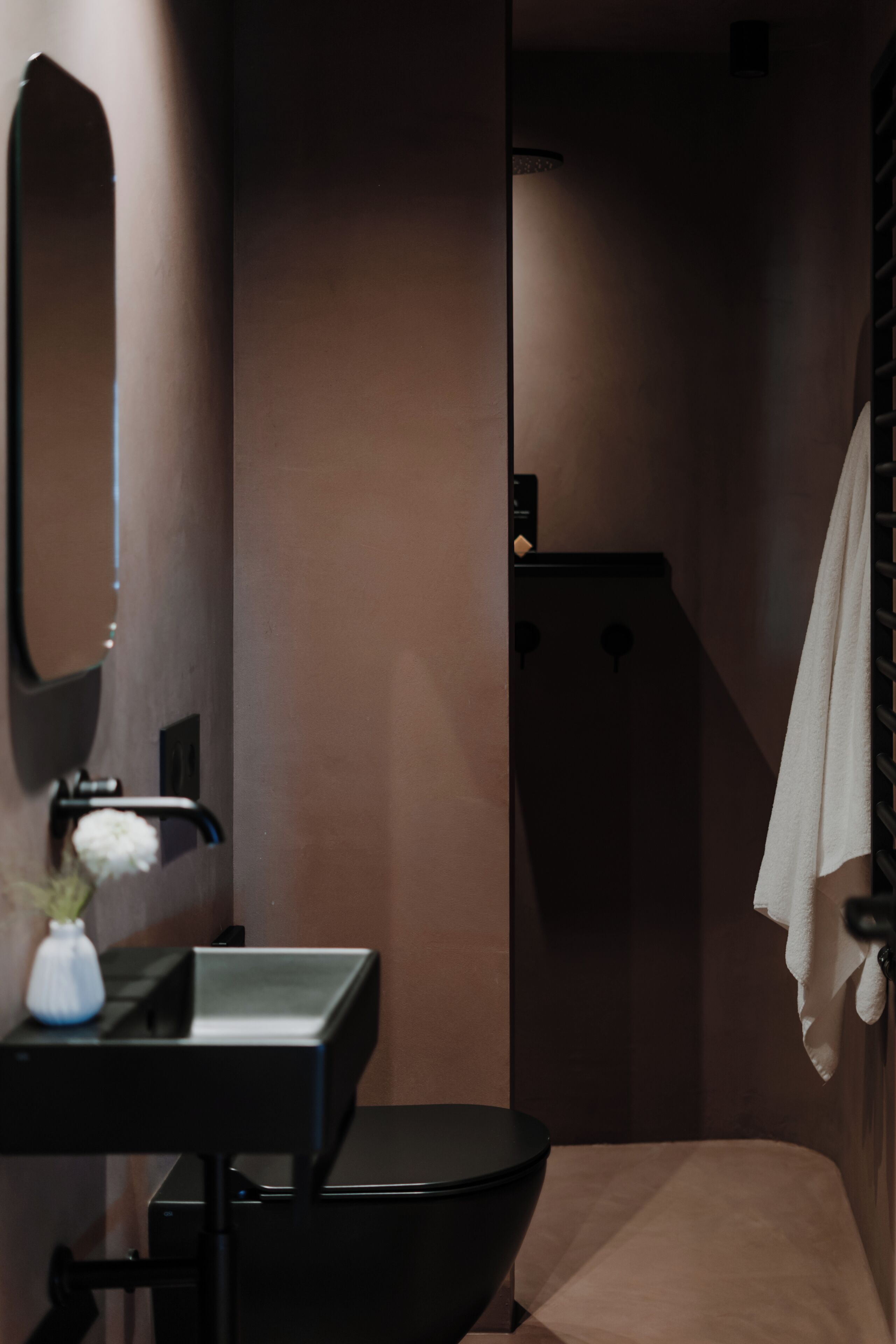 Un baño con lavamanos negro, espejo y inodoro.