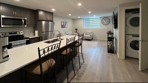 Eine moderne Küche mit Kochinsel, Edelstahlgeräten und einem Essbereich mit Sofa und Stühlen.