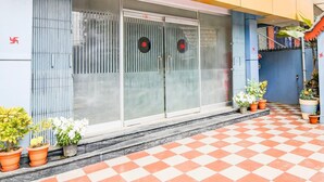 Een gebouw met grote glazen deuren, plantenpotten en een zwart-wit geruit vloer.