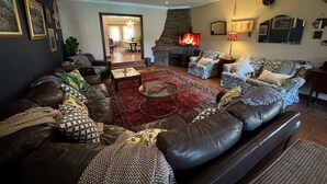 Ein Wohnzimmer mit Kamin, Ledersofas, einem Couchtisch und einer Steinwand.