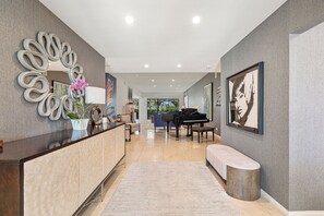 A modern lobby with a reception desk, a piano, seating area, and artwork on the walls. - Courtside Escape - Country Club Living (Rancho Mirage)