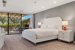 Une chambre d’hôtel avec un grand lit, deux tables de chevet, une chaise et une vue sur la verdure.