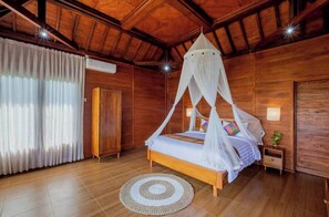 A wooden room with a bed, a round rug, and a canopy bed.
