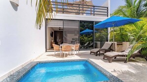 Ein moderner Außenpoolbereich mit einer verglasten Terrasse, Liegestühlen und Sonnenschirmen.