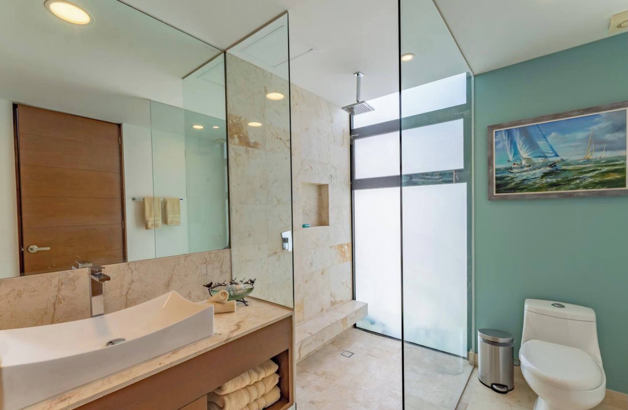 Une salle de bain moderne avec un grand miroir, un lavabo, des toilettes et une douche.