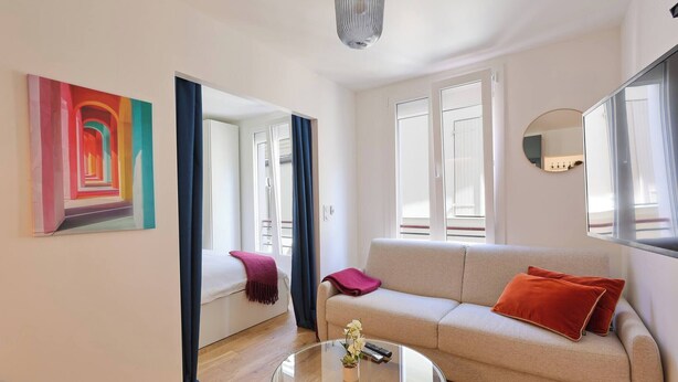 Ein Wohnzimmer mit einer Couch, einem Glastisch, einem Gemälde und einem Spiegel.