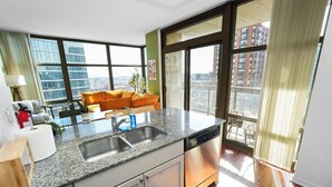 A modern kitchen with granite countertops, stainless steel appliances, and a large window offering a city view. - Skyline 2BR Heart of Chicago Walk to Grant Park (Chicago)