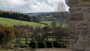 A stone wall, a fenced area, and a view of rolling hills and trees. - Blackhill barn - in the heart of the Cotswolds (Craswall)