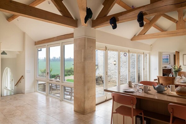 A spacious dining area with a view of the outdoors, wooden beams, and a table set for dining.