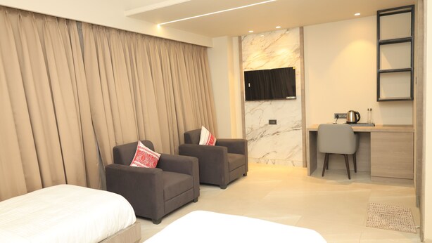 Una habitación de hotel moderna con una cama, dos sillones, un escritorio y un televisor.