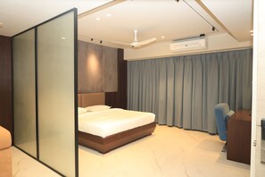Quarto de hotel moderno com uma cama grande, uma escrivaninha, uma cadeira e uma porta de correr.