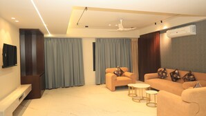 Una sala de estar moderna con un sofá, sillones, una mesa de centro y un televisor de pantalla plana montado en la pared.