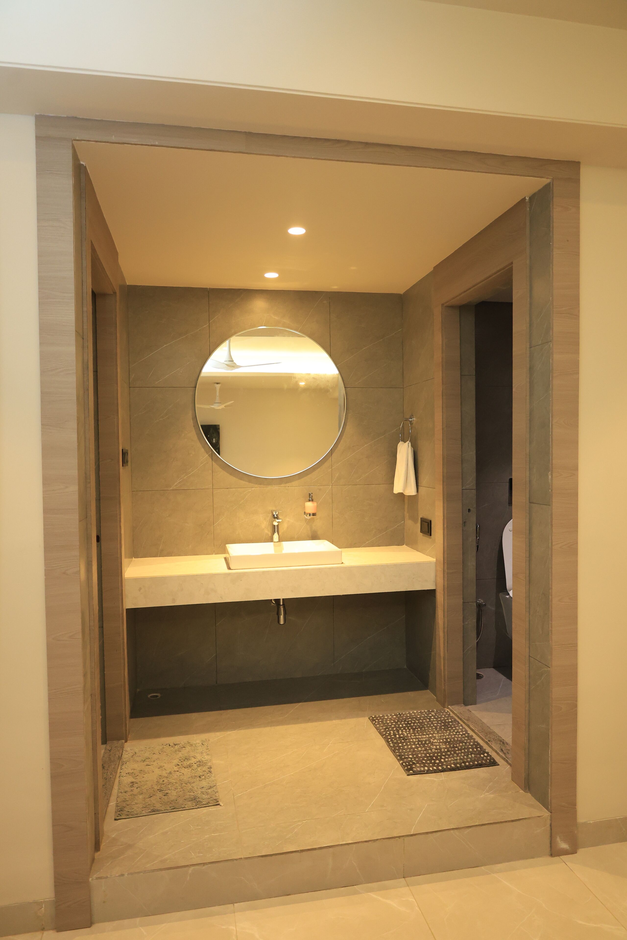 Un baño moderno con un espejo redondo, un lavamanos y una zona de ducha.