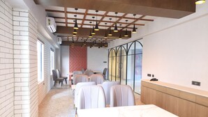 Un salón de conferencias con una larga mesa, varias sillas, una alfombra estampada, un muro de ladrillo y un techo de madera.