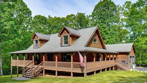 A log cabin with a porch, a staircase, and a flag. - Hot Tub & Patio: Bedford Log Cabin on 10 Acres! (Bedford)