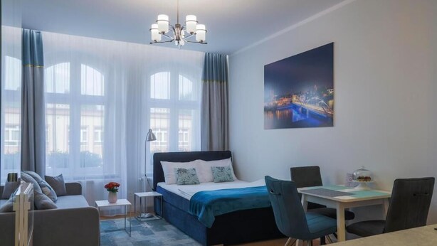 Une chambre d’hôtel moderne équipée d’un lit, d ’un bureau, d’une chaise, d’un canapé et d’une grande fenêtre avec des rideaux.