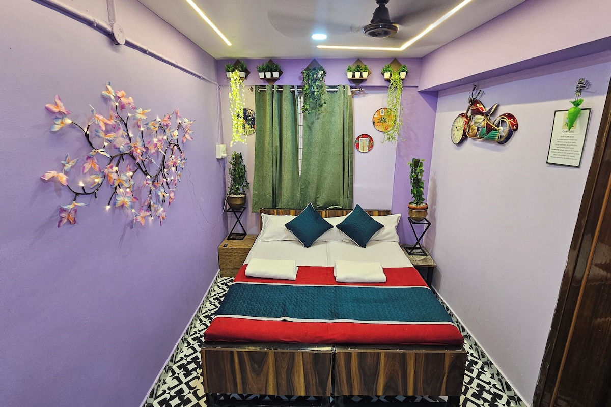 A narrow room with a bed, green curtains, and a wall-mounted clock.