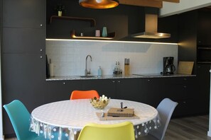 Eine moderne Küche mit einem runden Esstisch, Stühlen und einer Kaffeemaschine.