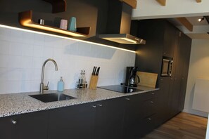 Eine moderne Küche mit dunklen Schränken, einer Granit-Arbeitsplatte, einer Edelstahl-Spüle und einem eingebauten Backofen.