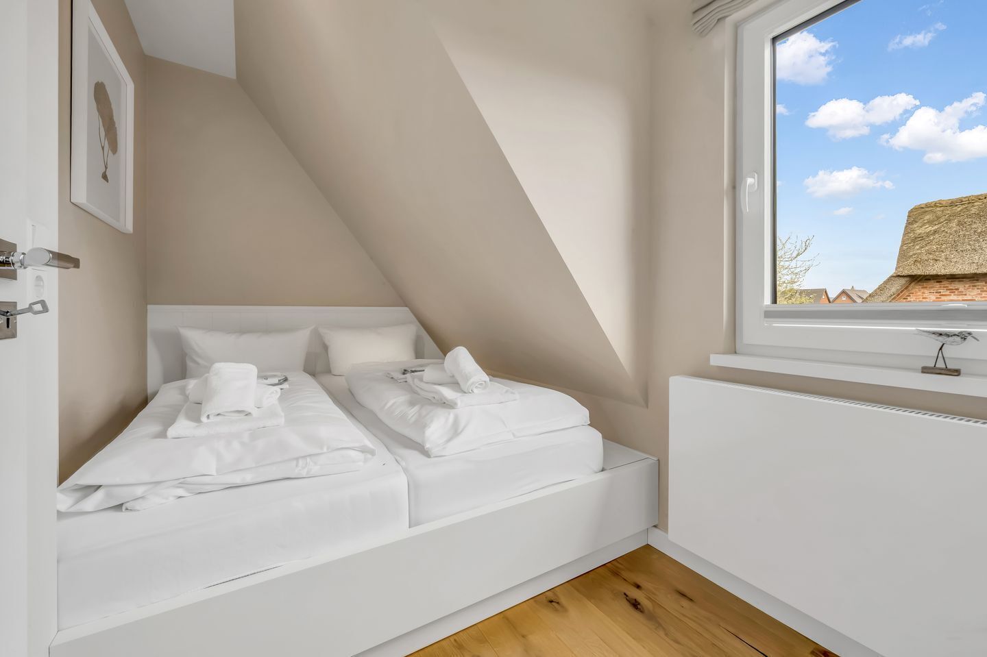 Un dormitori petit d'estil loft, de color blanc, amb una finestra que donava a un edifici de maó.