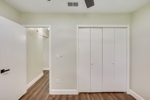Un pasillo con una puerta blanca, un armario blanco y suelo de madera.