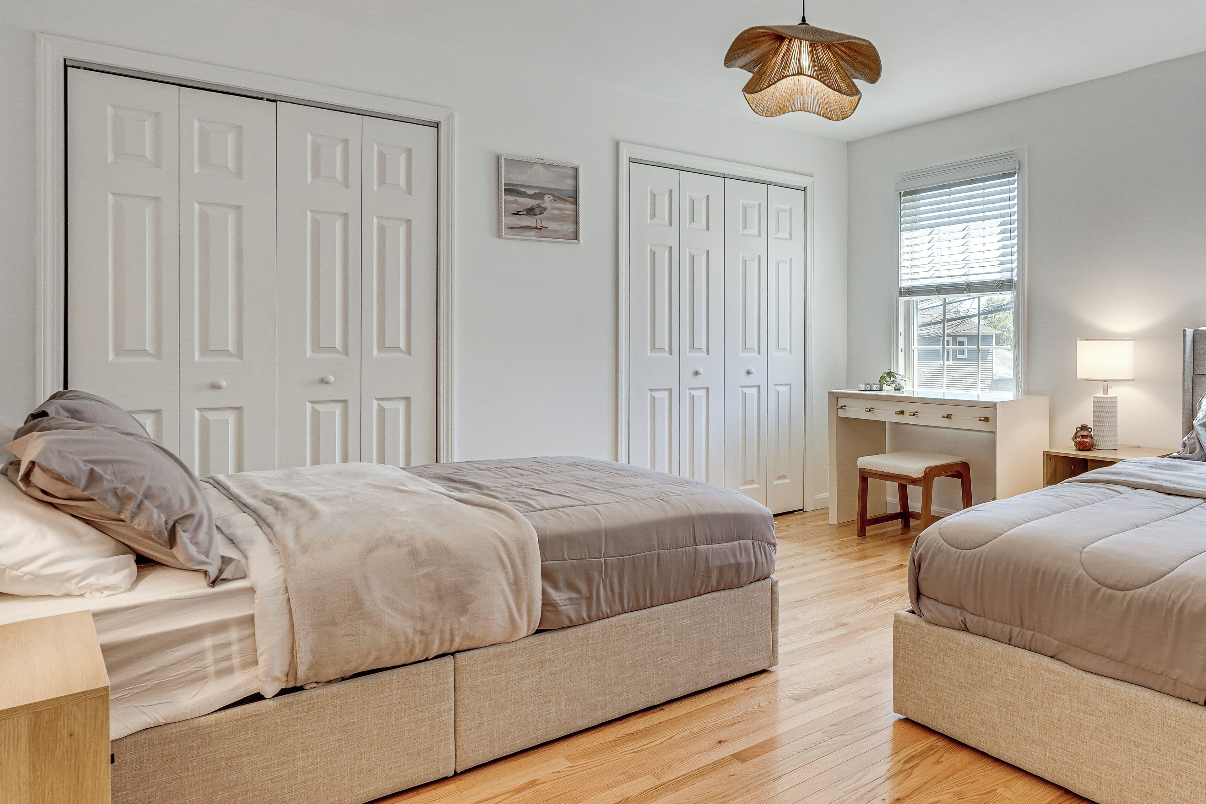 A bedroom with two beds, a desk, and a window.