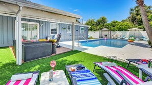 A backyard with a swimming pool, sun loungers, a covered patio, and a small deck area. - Outdoor Oasis & All-Ages Fun! Gulf Coast Getaway (Hudson)