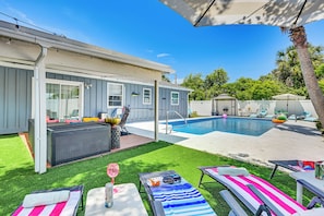 Ein Garten mit Pool, Liegestühlen, einer überdachten Terrasse und einer kleinen Holzterrasse.