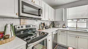 A kitchen with white cabinets, a stainless steel microwave, a double oven, and a dishwasher. - Outdoor Oasis & All-Ages Fun! Gulf Coast Getaway (Hudson)