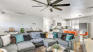 A modern living room with a sectional sofa, a wooden coffee table, and a ceiling fan. - Outdoor Oasis & All-Ages Fun! Gulf Coast Getaway (Hudson)